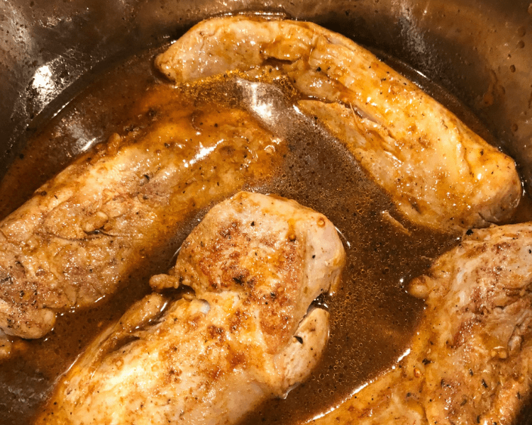 Cooked pork tenderloin pieces in their juices in an Instant Pot.