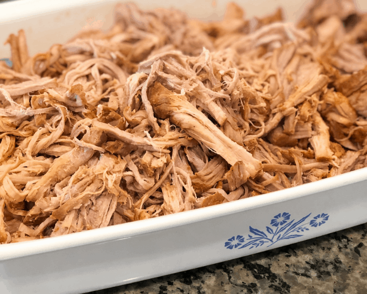 Instant Pot Pulled Pork Tenderloin in a serving dish on a kitchen countertop.