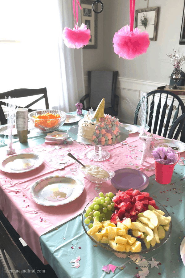 Table settings, pink tablecloth, and a unicorn birthday cake for a unicorn-themed birthday party.