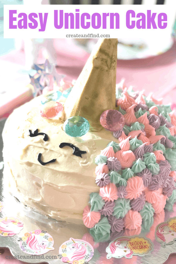 A homemade unicorn birthday cake with a gold horn, smiley face and pink, purple, and teal designs.