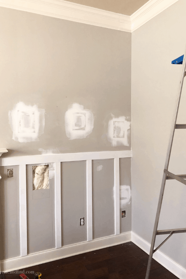 Progress shot of a DIY board and batten accent wall and a metal ladder.