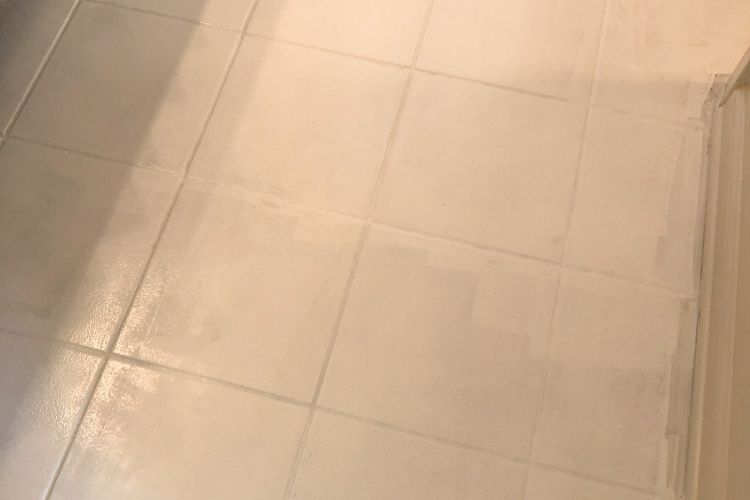 Close-up of square bathroom floor tiles that have been painted white.