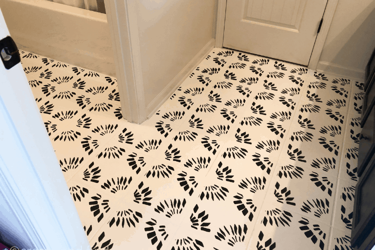 Painted bathroom floor tiles with a black stencil design.