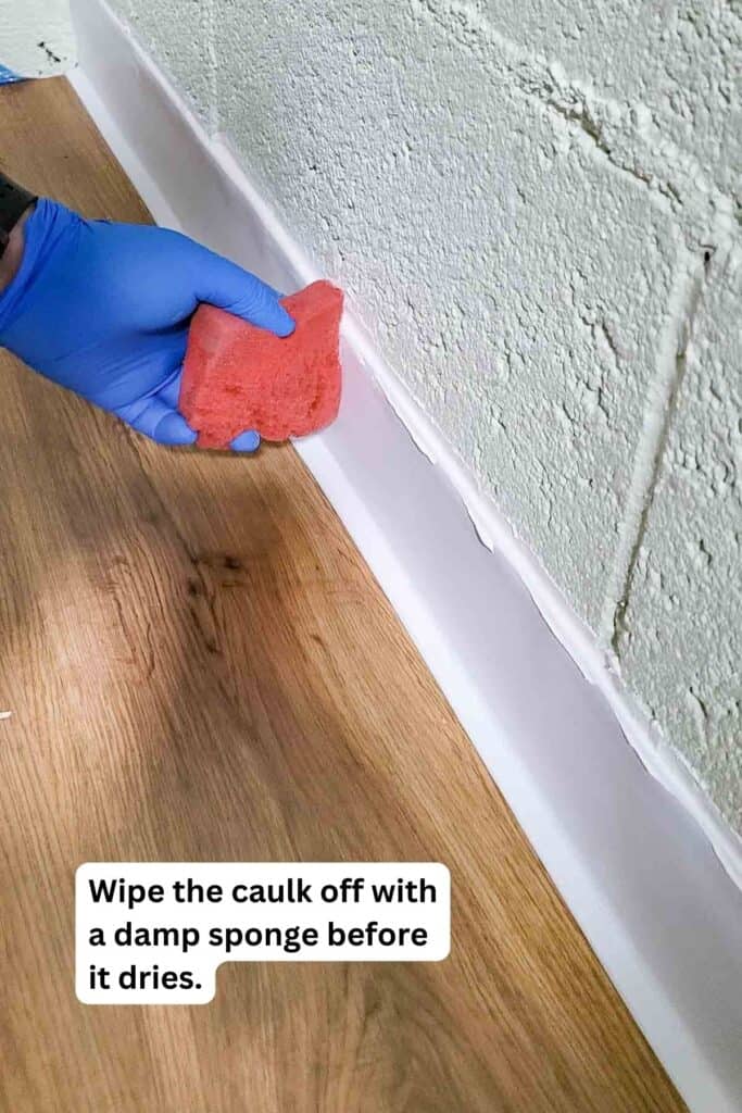 Wiping off excess caulk from wall base.