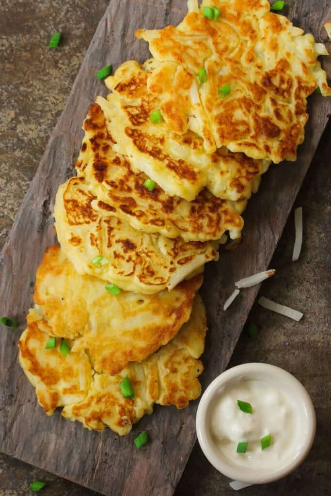 Irish potato fritters on a wooden cutting board with white dipping sauce.