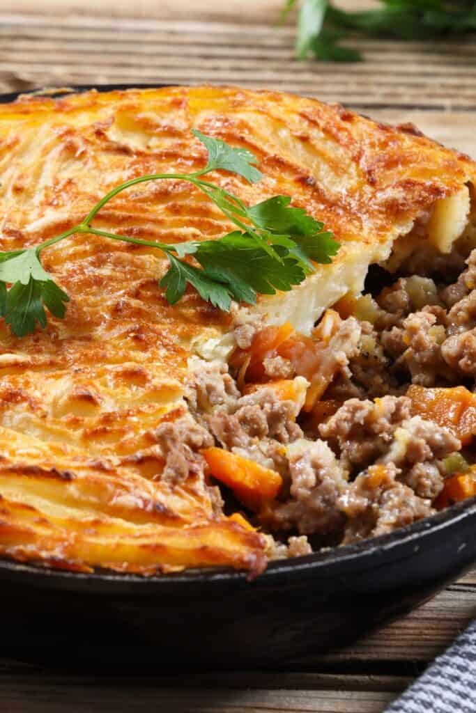 Cottage pie in a large black skillet with green garnish.