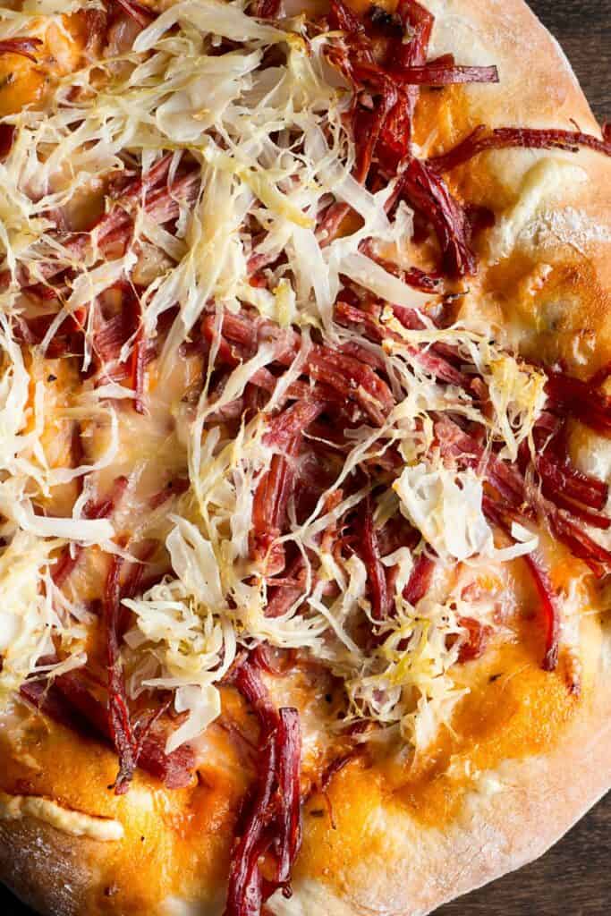 A Reuben pizza with sour kraut, shredded beef, and cheese.