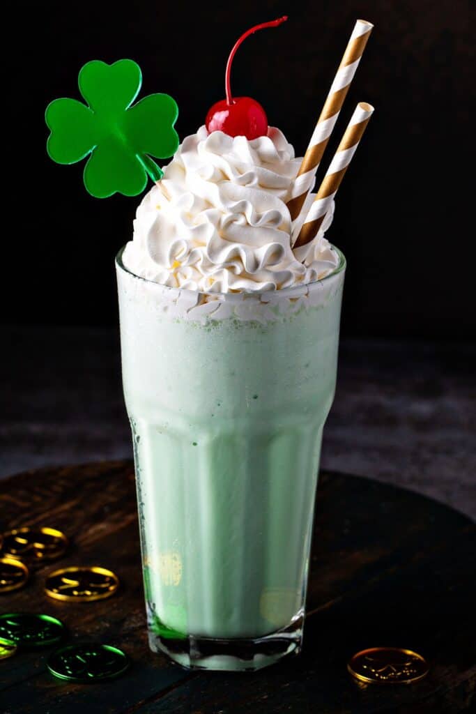 A green milkshake with a shamrock topper, whipped cream, and a cherry.