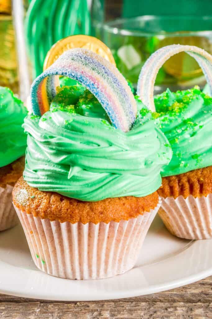Cupcakes with green icing and rainbow strip candies on top.