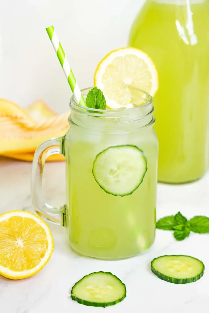 Cucumber lemonade in a mason glass jar with a white and green striped straw.