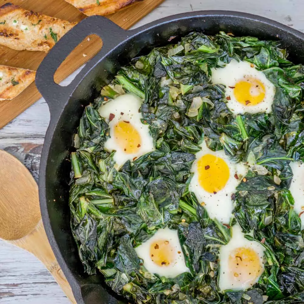 Collard green and kale shakshuka in a large cast iron skillet.