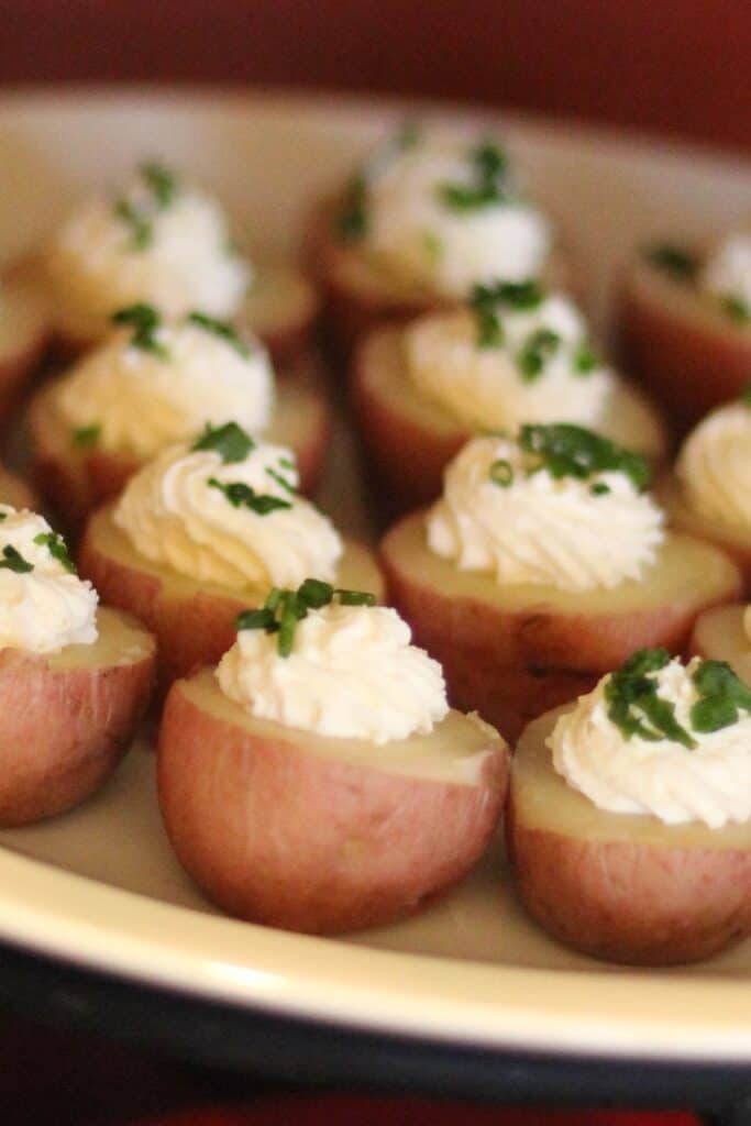 Irish potato bites appetize with cream and green garnish on top.
