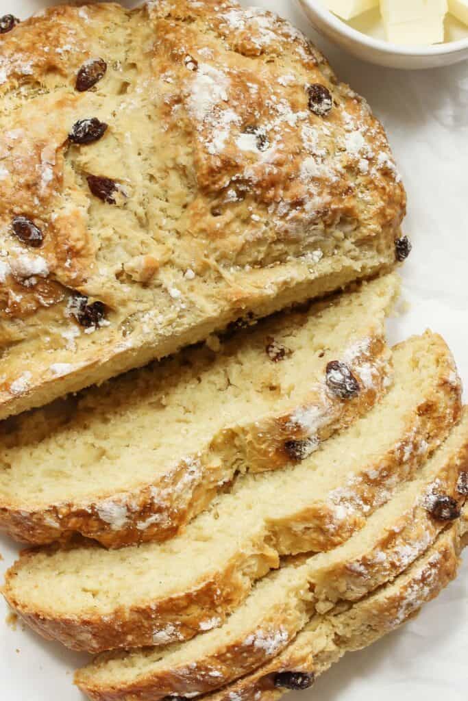 A loaf of Irish soda bread with several slices cut into it.