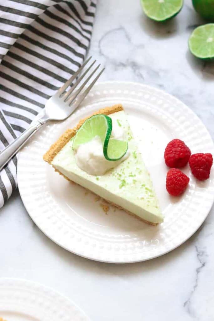 Vegan key lime pie slice on a white plate with lime wedge garnish.