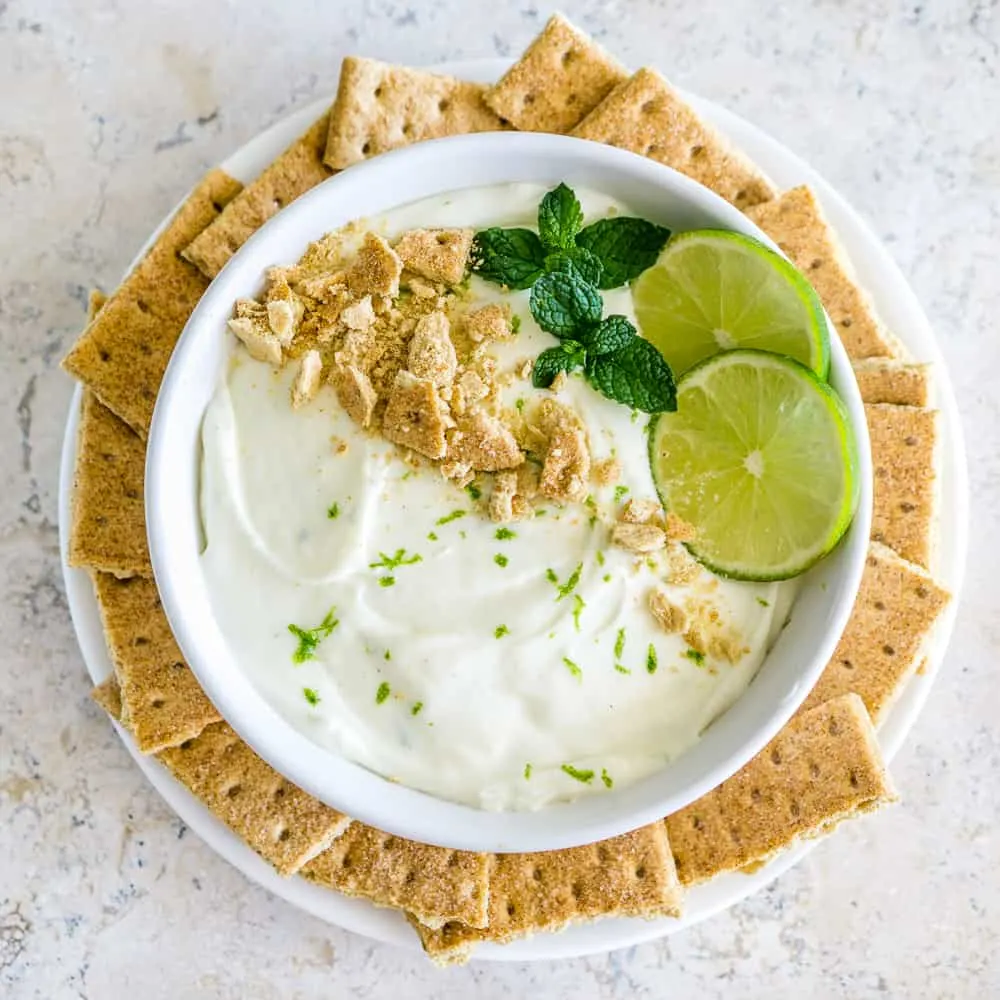 Key lime pie cheesecake dip with graham crackers, mint garnish, and lime slices.