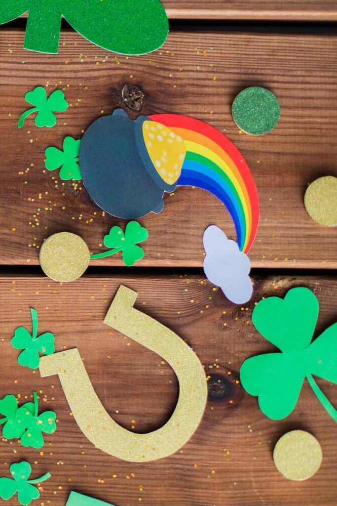 Horseshoes, shamrocks, coins, and a rainbow pot of gold, on a table for decor.