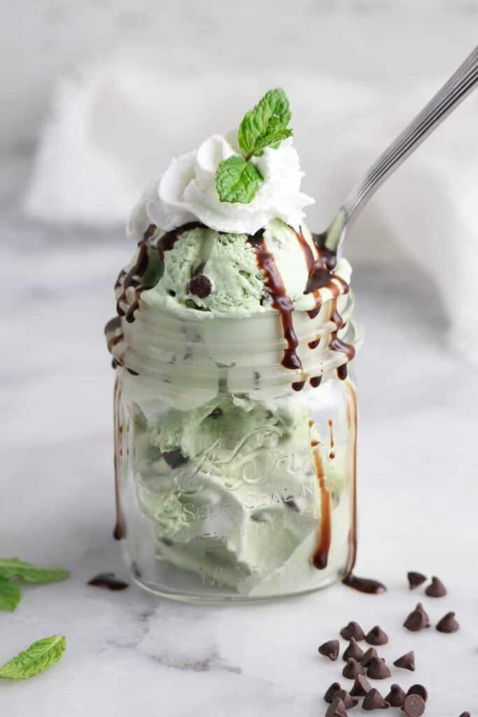 Mint chocolate shake in a mason jar with chocolate chips and mint garnish.