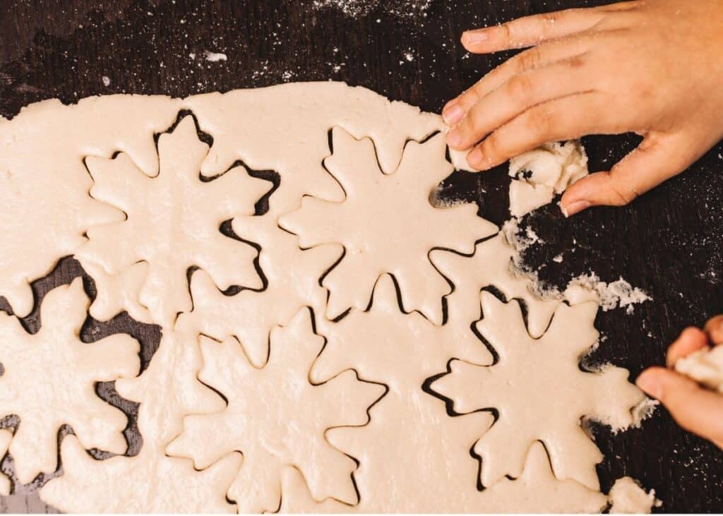 Rolled dough on a counter with several snowflake cutouts.