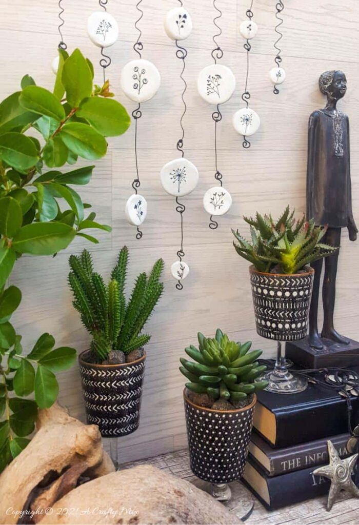 A DIY clay wall hanging with clay discs and coiled metal.