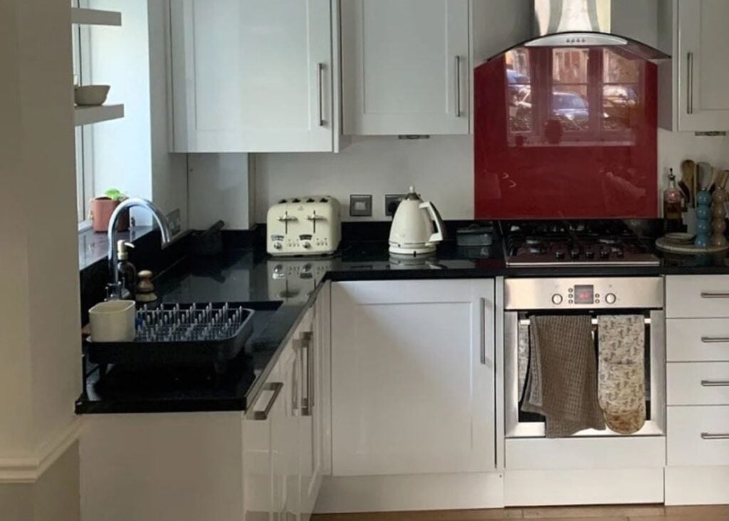 A kitchen with a black countertop and red backsplash tile.