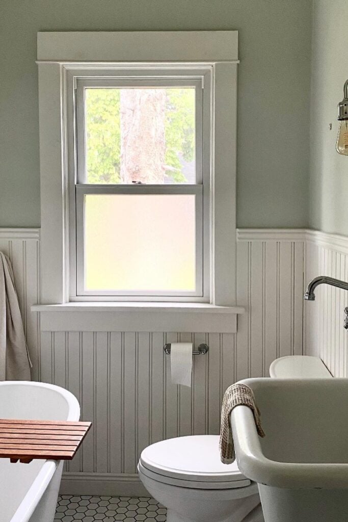 A bathroom with light green walls and board and batten.