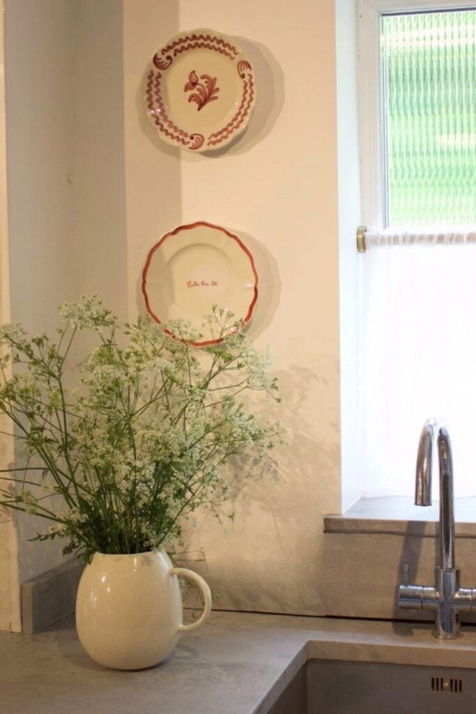 Vintage Plates on a kitchen wall next to a window for decor.