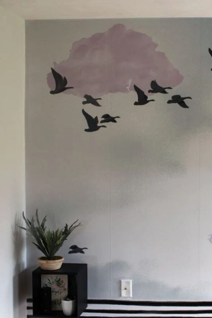 A wall mural in an entryway with a somber sky and black birds.