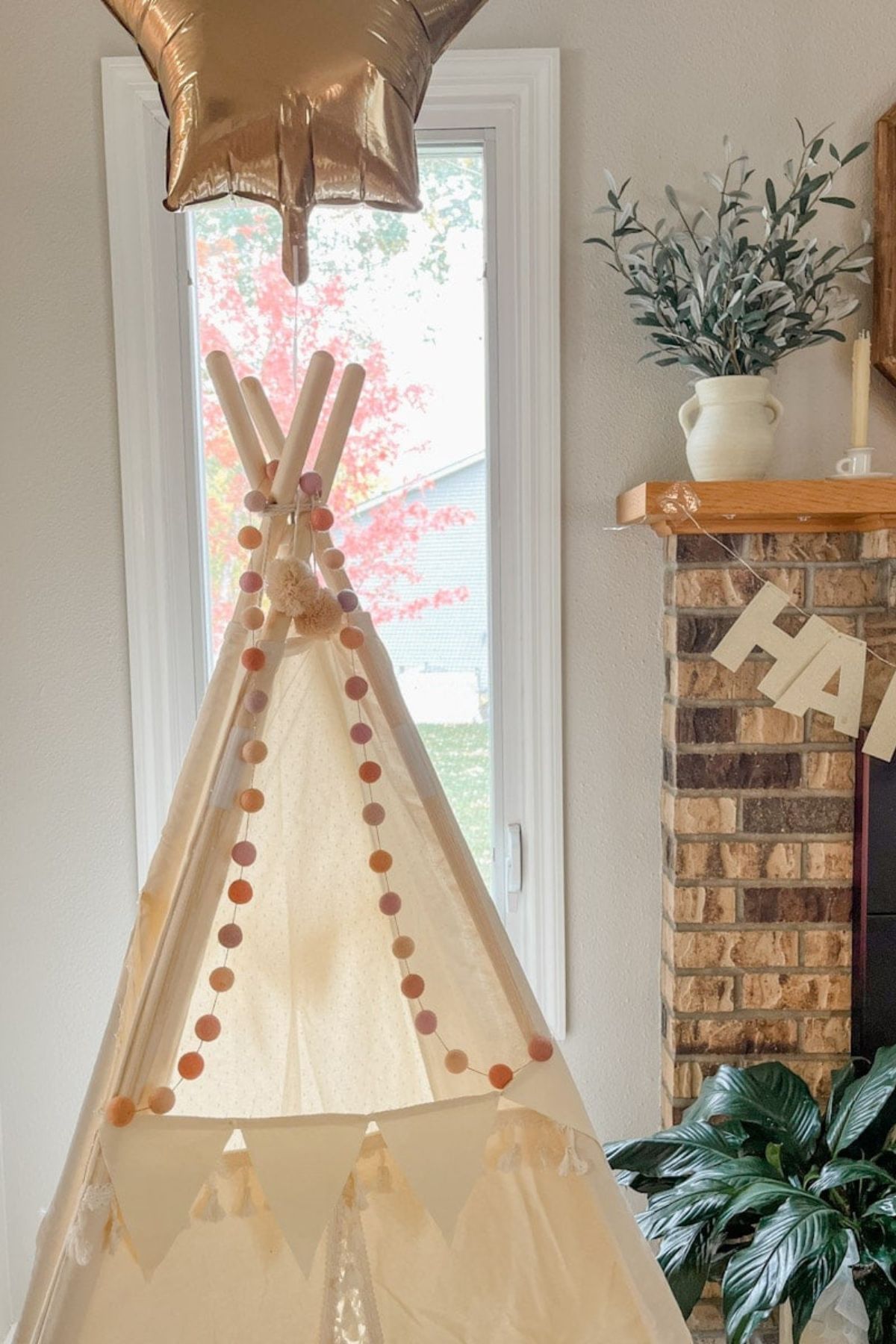 A DIY pom pom garland hanging from an child's indoor teepee.