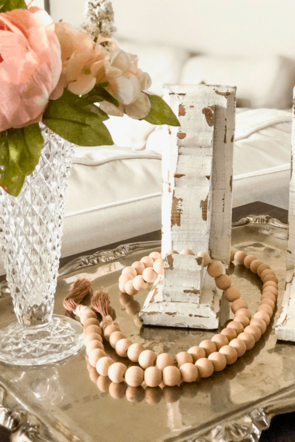 A wood bead garland around a farmhouse weathered white corbel on a coffee table. 