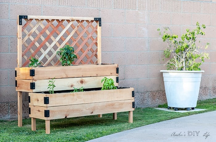 DIY tiered raised garden bed against a fence outside.