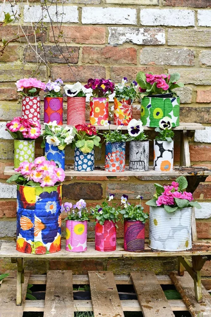 Painted tin can planters with colorful flowers.
